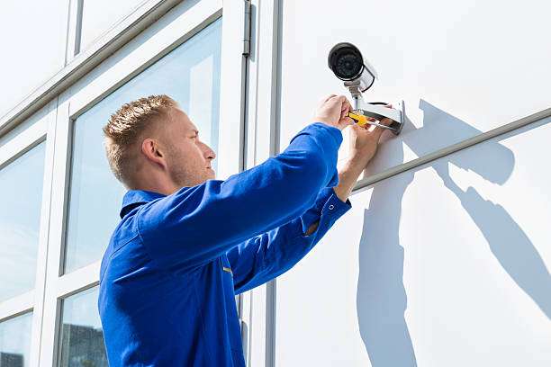 Technician Fixing Camera On Wall With Screwdriver | Rest-A-Sured Security Technician fitting a wall mounted camera using a screwdriver