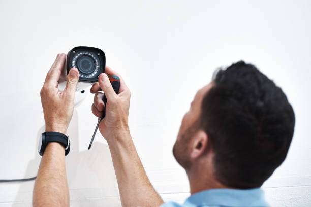 Shot of a mature man installing a security camera on a building